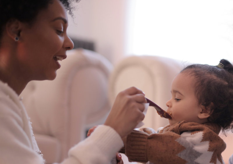 Mama füttert Kind mit Brei