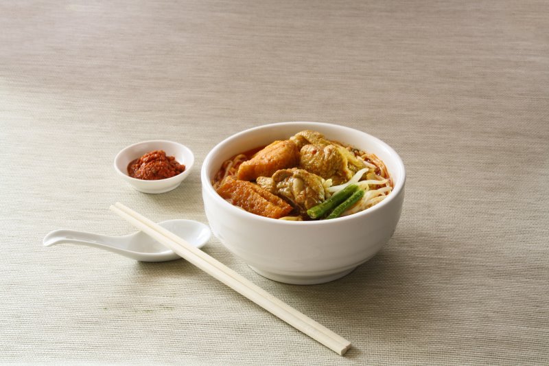 Essstäbchen und Löffel neben einer asiatischen Suppe