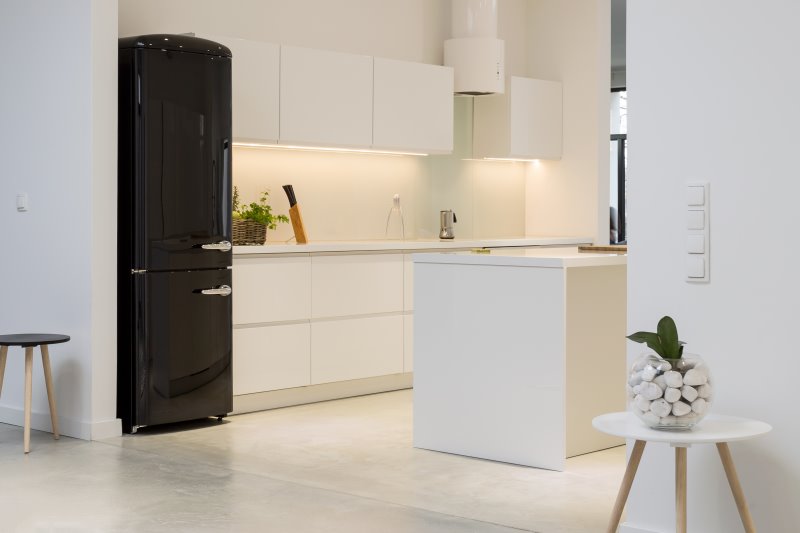 Moderne helle Küche mit einem schwarzen freistehenden Retro-Kühlschrank.
