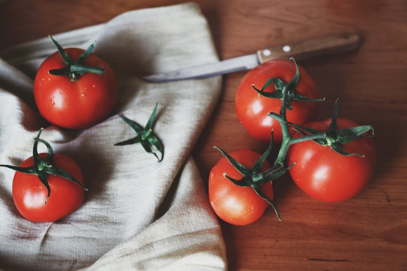 Tomatenmesser liegt neben frischen Tomaten auf einem Geschirrtuch.